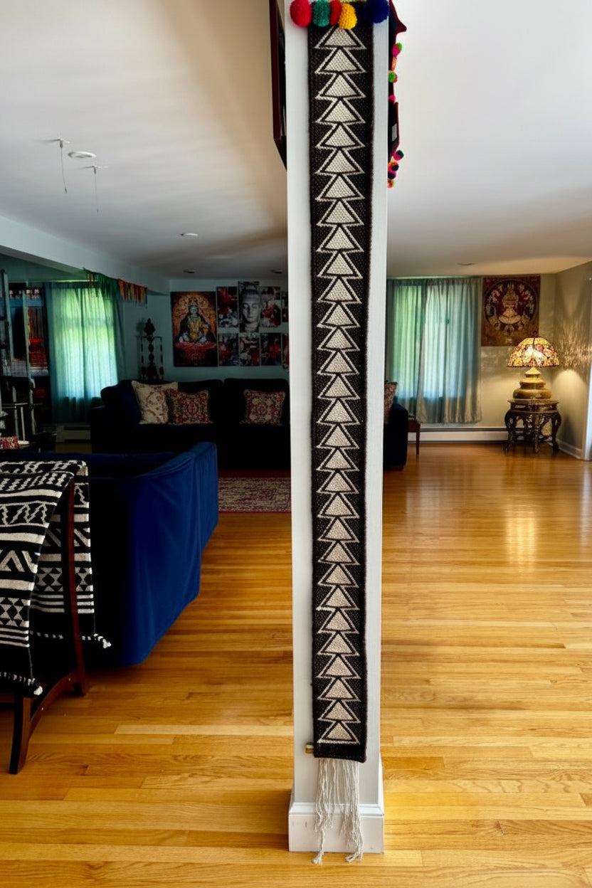Decorative Kutchi Kharad wool totem rug with geometric pattern in a room with wooden flooring and furniture.