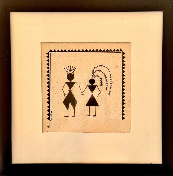 A framed Chittara art motif hand drawn painting featuring a minimalist black tribal-style illustration of two figures holding hands on a square beige paper background, surrounded by a wide cream mat and a dark frame.