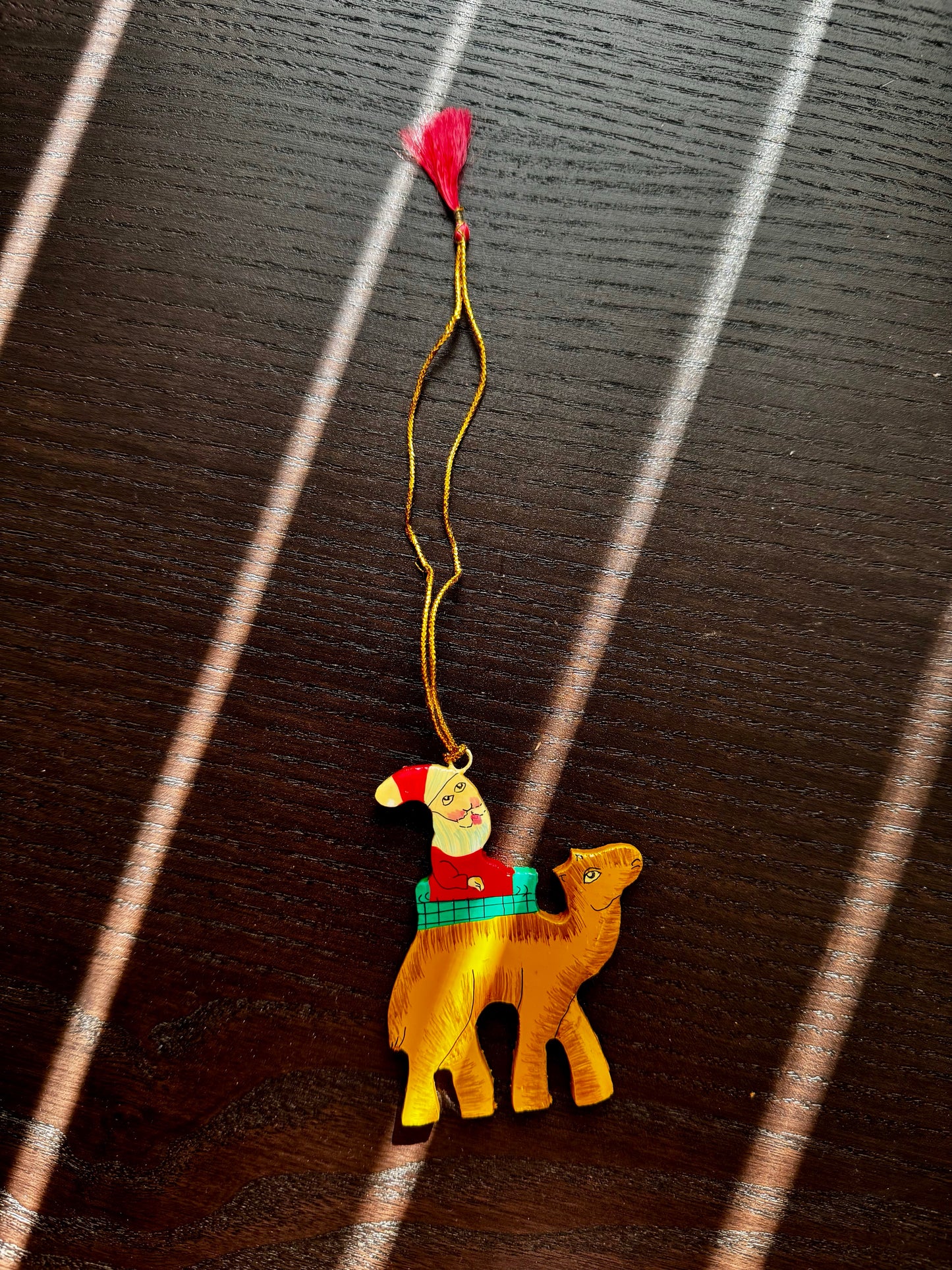 Decorative camel ornament with Santa and a red heart on a dark wooden surface
