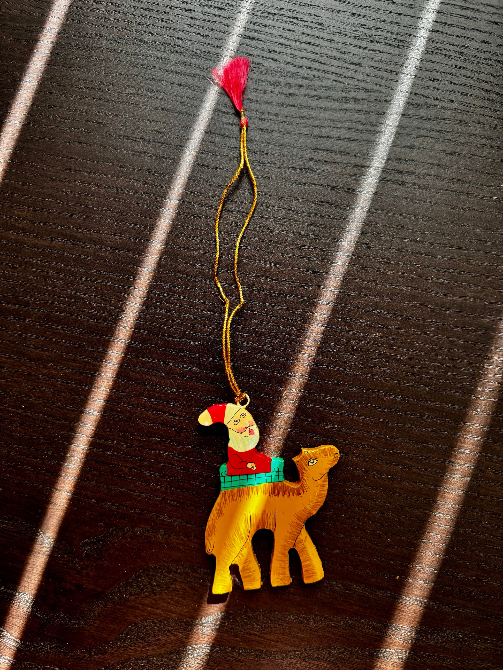 Decorative camel ornament with Santa and a red heart on a dark wooden surface