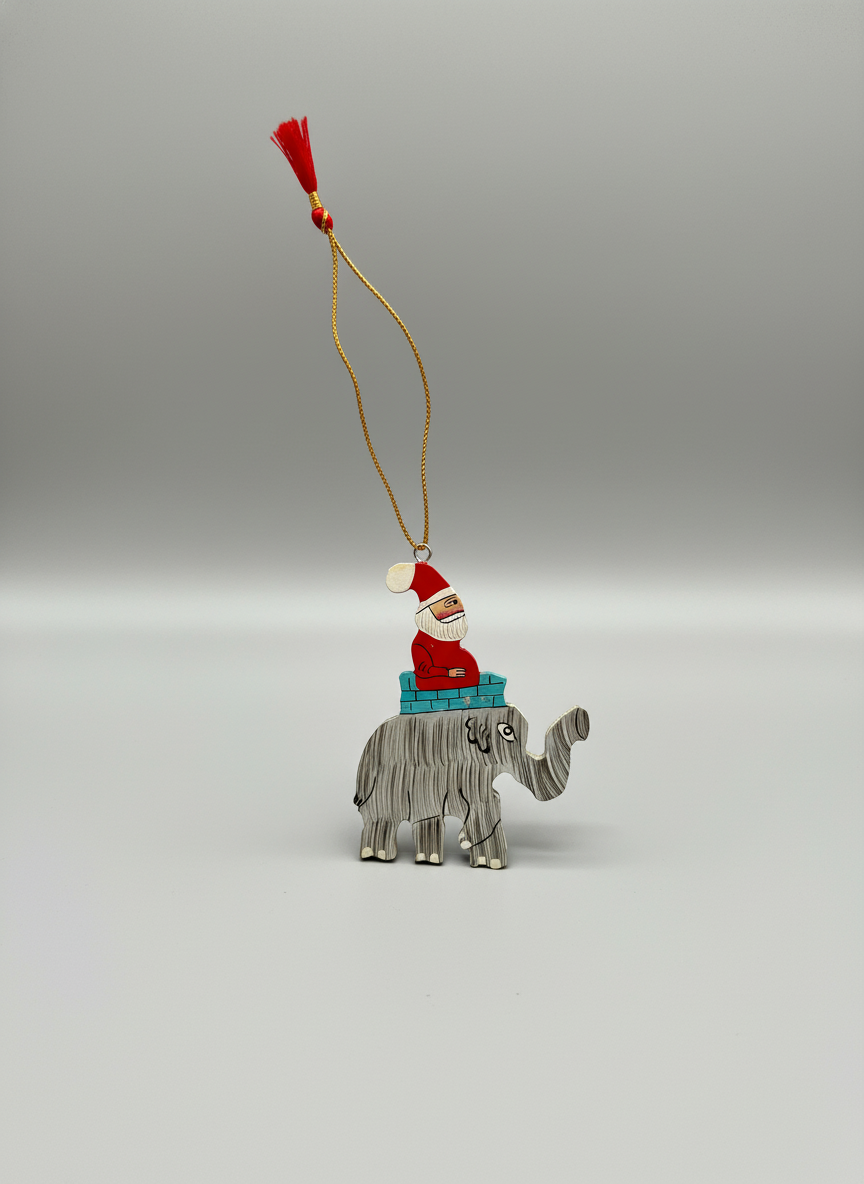 Christmas ornament with a Santa Claus figure on an elephant, hanging from a string against a gray background.