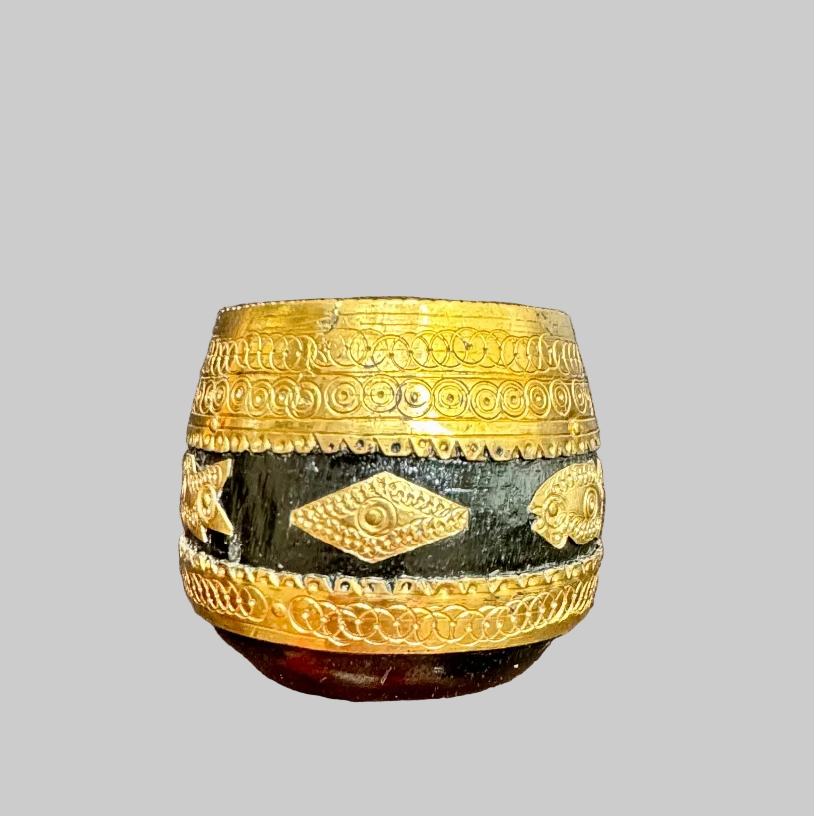 Decorative wood Sherpai bowl with brass embellishments on a gray background
