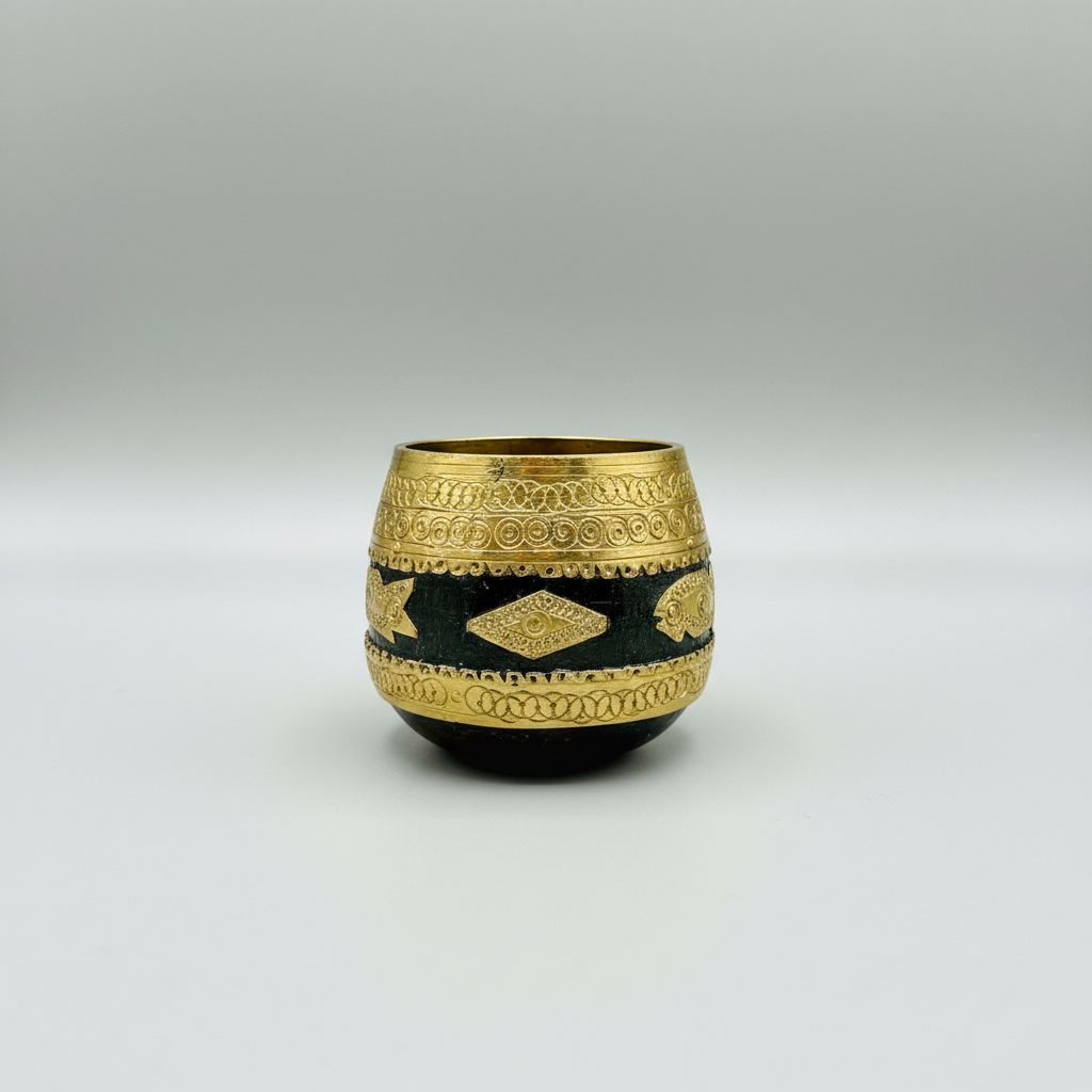 A small decorative Wood and brass Sherpai small bowl with a dark body and ornate gold metallic bands, photographed against a neutral gray studio background.