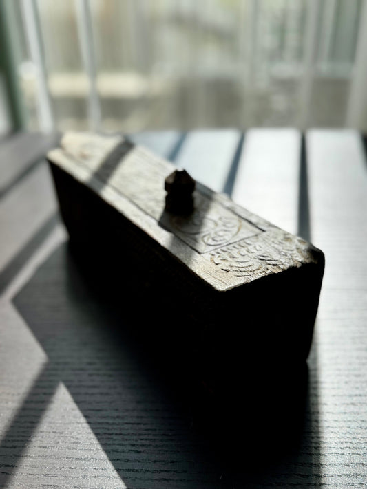 Decorative wood box with intricate carvings on a reflective surface