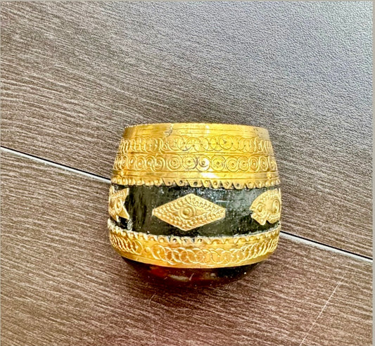 Decorative wood and brass Sherpai bowl  with gold patterns on a wooden surface