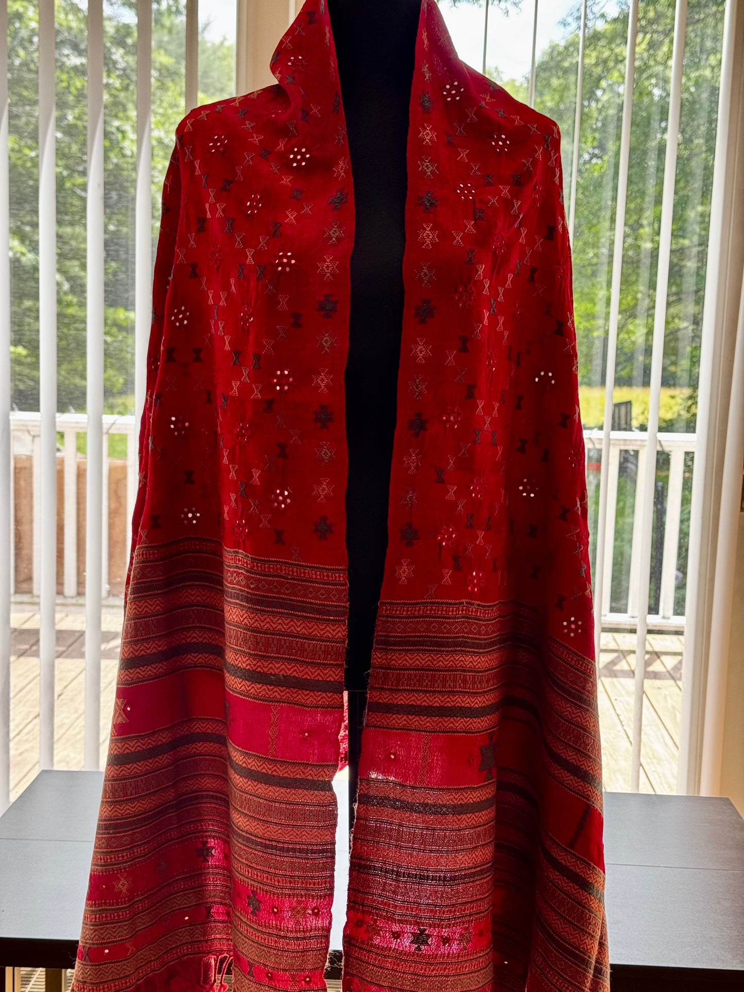 Red patterned Kutchi embroidery scarf on a mannequin against a window background