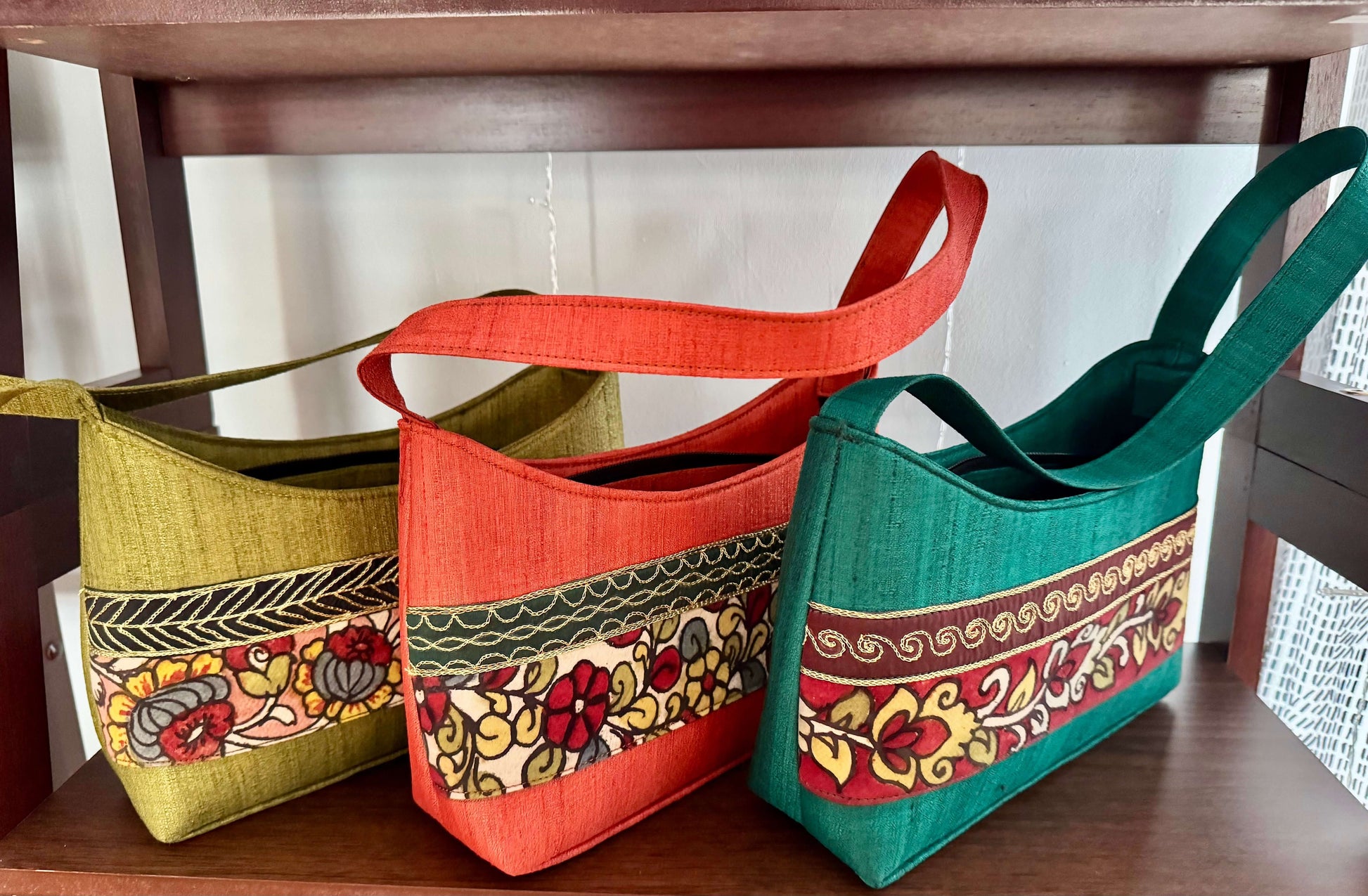 Three handbags with colorful patterns on a wooden surface.