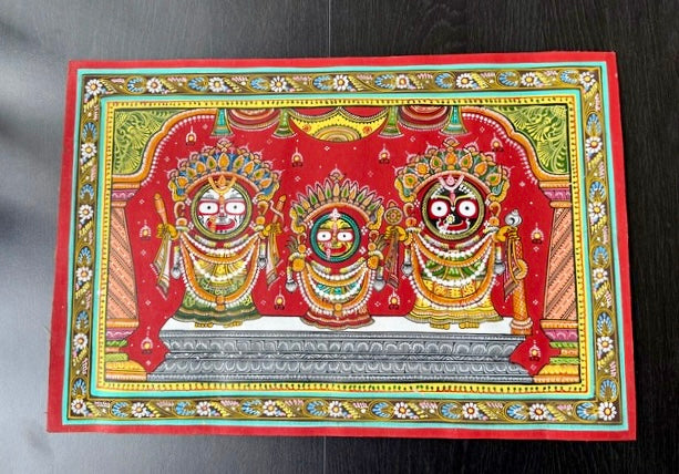 Decorative artwork with three deities in ornate attire on a red background