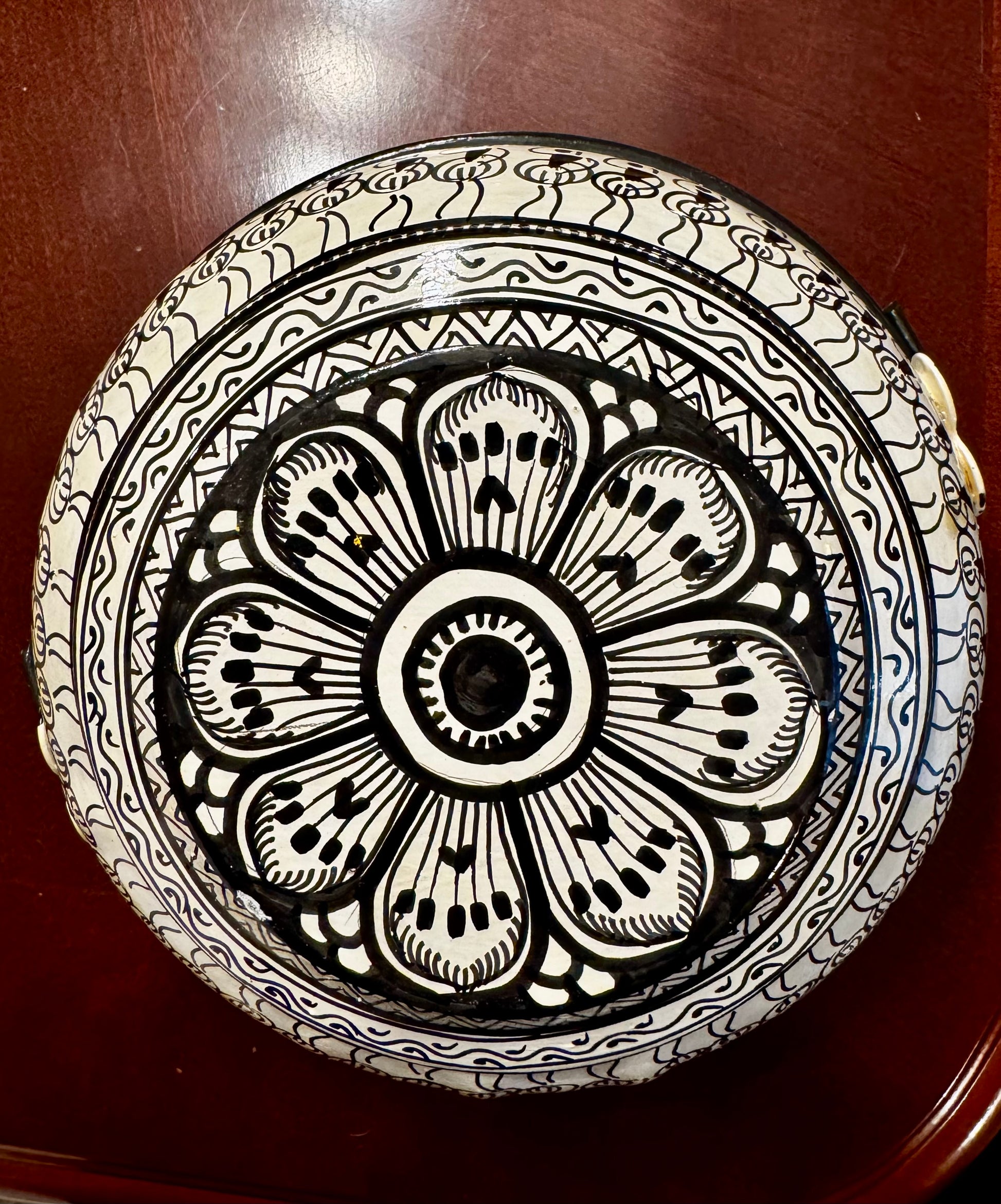 Decorative plate with black floral pattern on a wooden surface