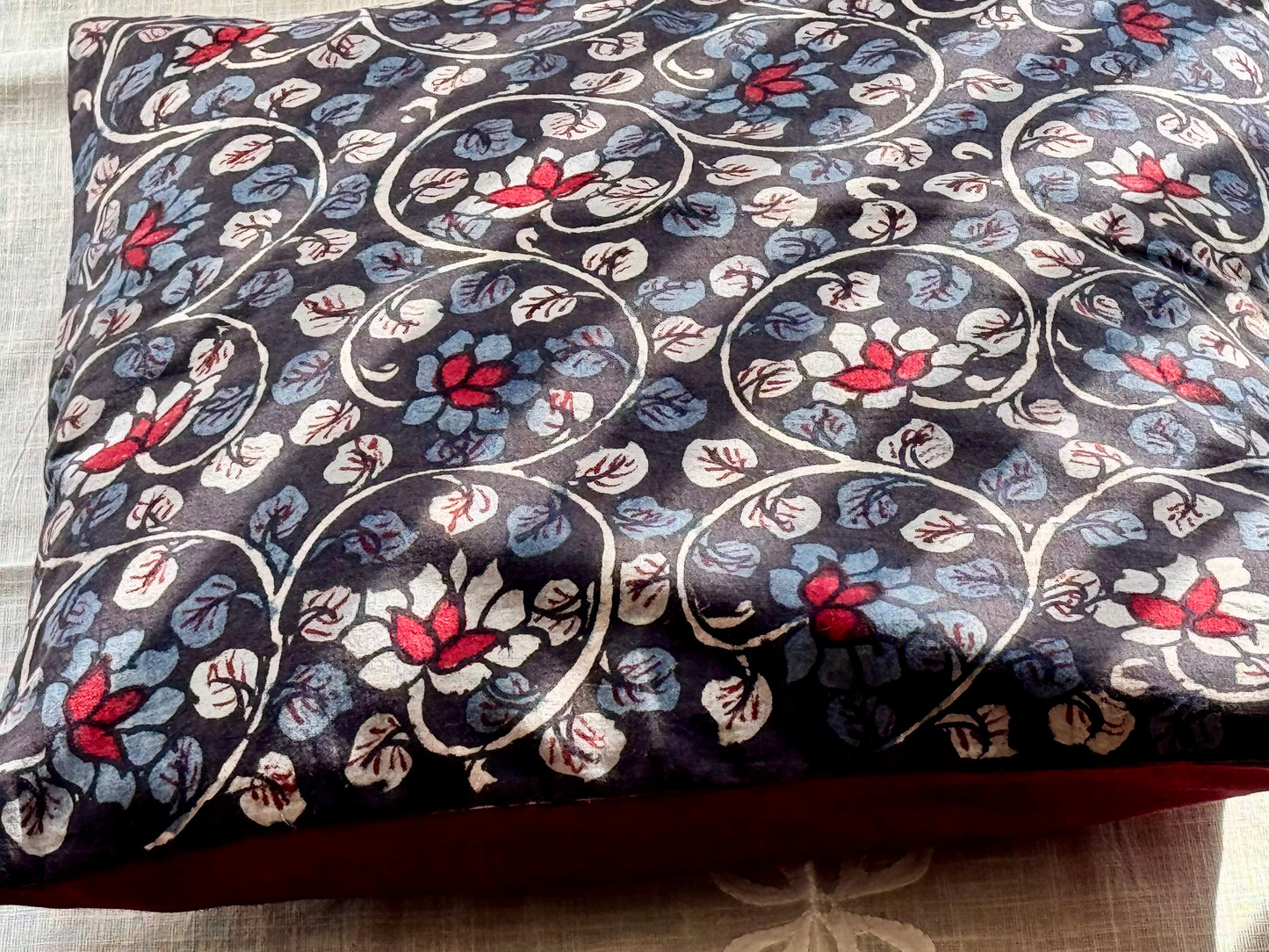 A set of artisanal Kalamkari hand-painted cushion covers with vibrant and intricate patterns laid out on a surface.