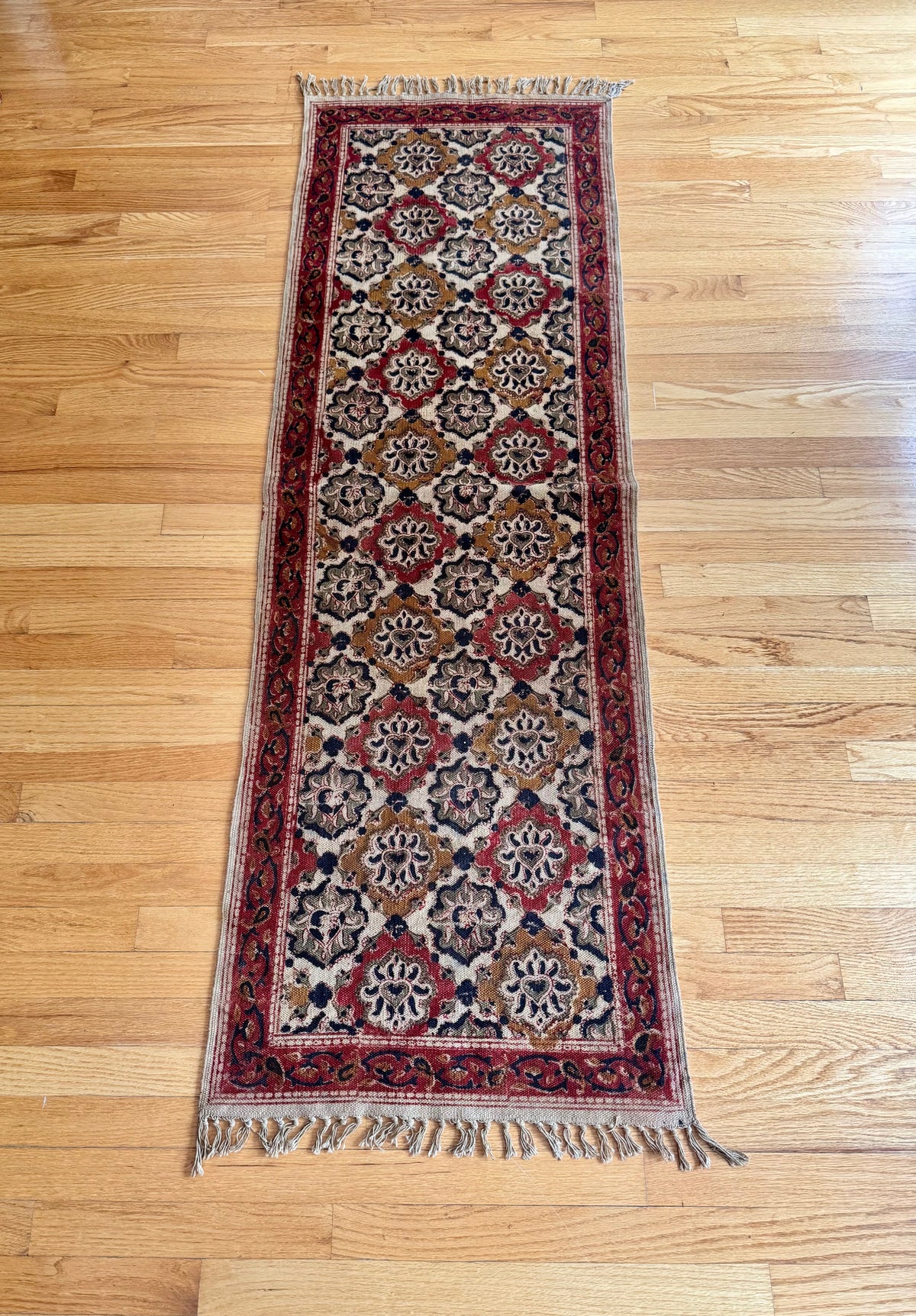 Decorative Warangal Kalamkari rug with intricate patterns on a wooden floor