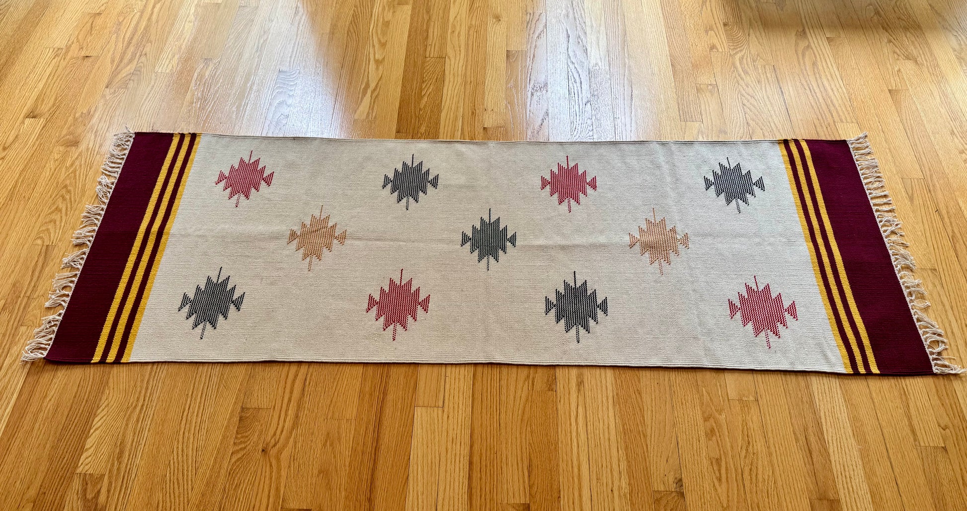 Decorative Warangal style Dhurrie rug with geometric pattern on a wooden floor