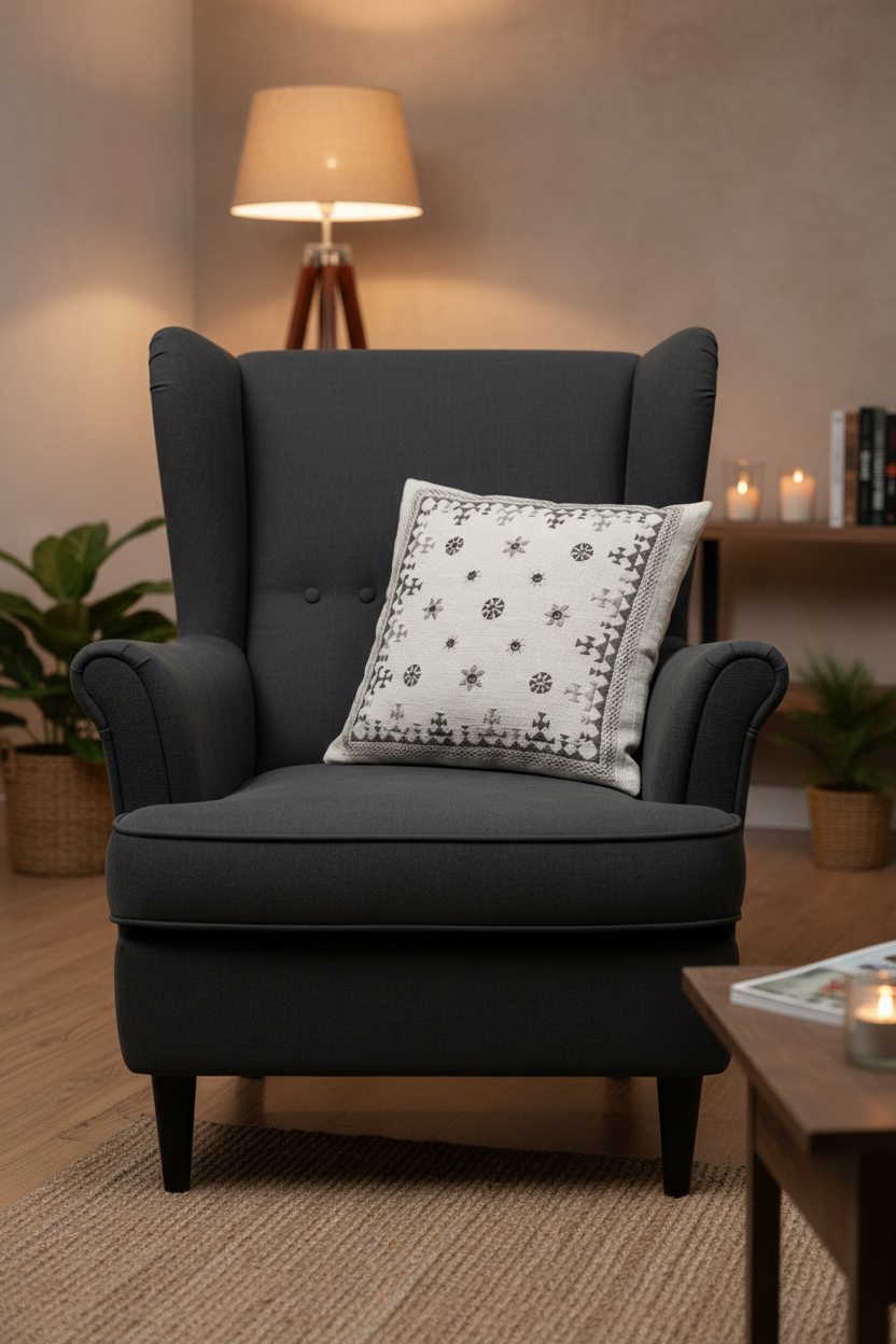 Gray armchair with a decorative pillow with Kutchi embroidery in a cozy living room setting.