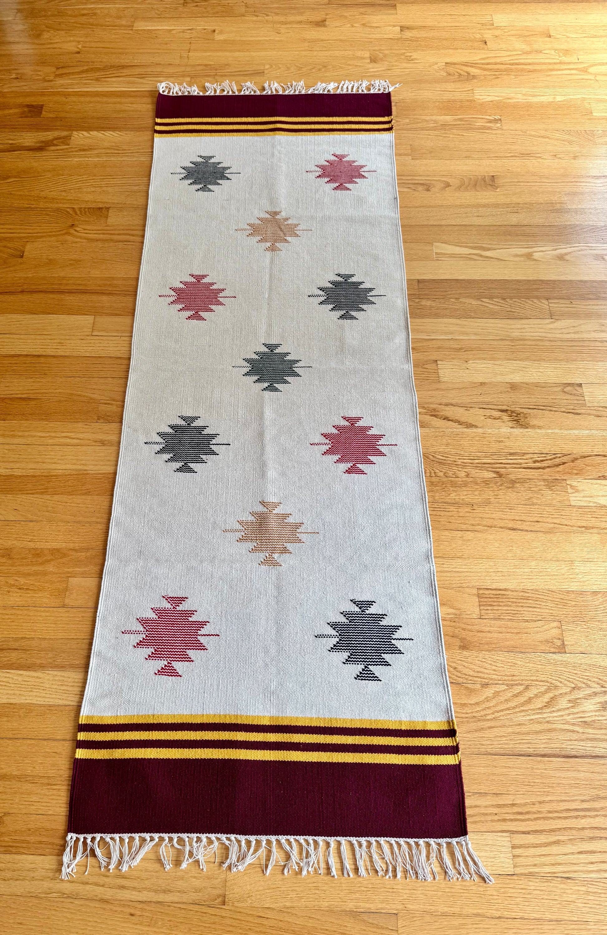 Woven Warangal style Dhurrie rug with geometric patterns on a wooden floor
