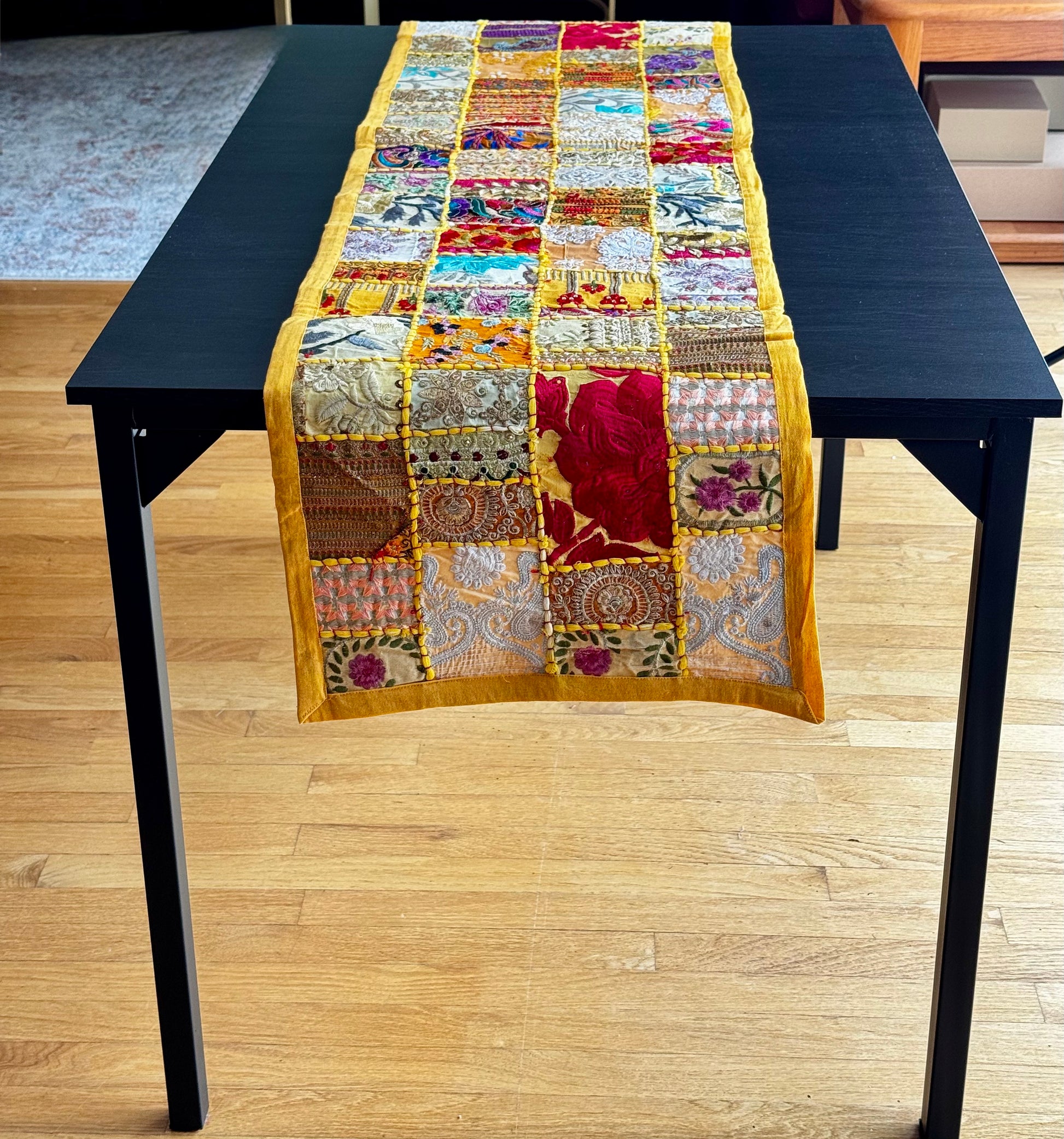 Colorful Khambhadia patchwork table runner on a black table