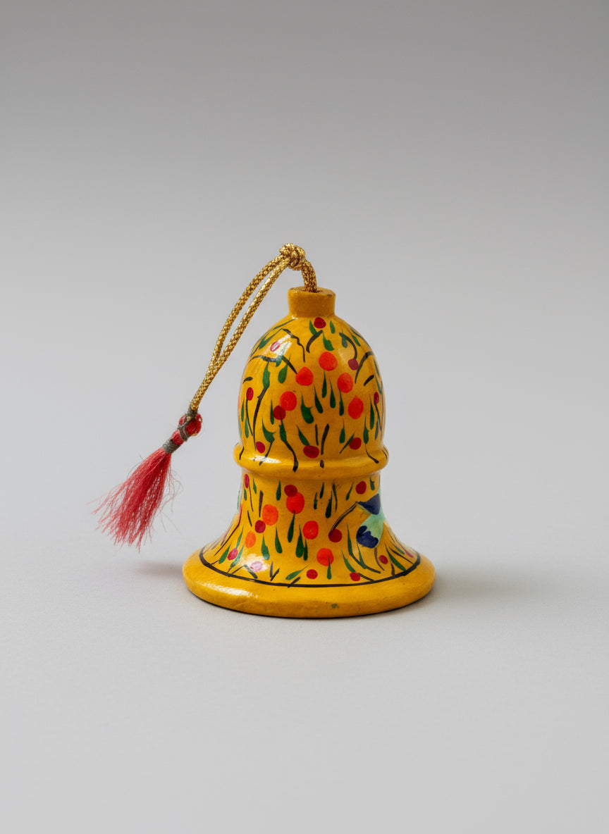 Decorative yellow bell with floral patterns on a wooden surface