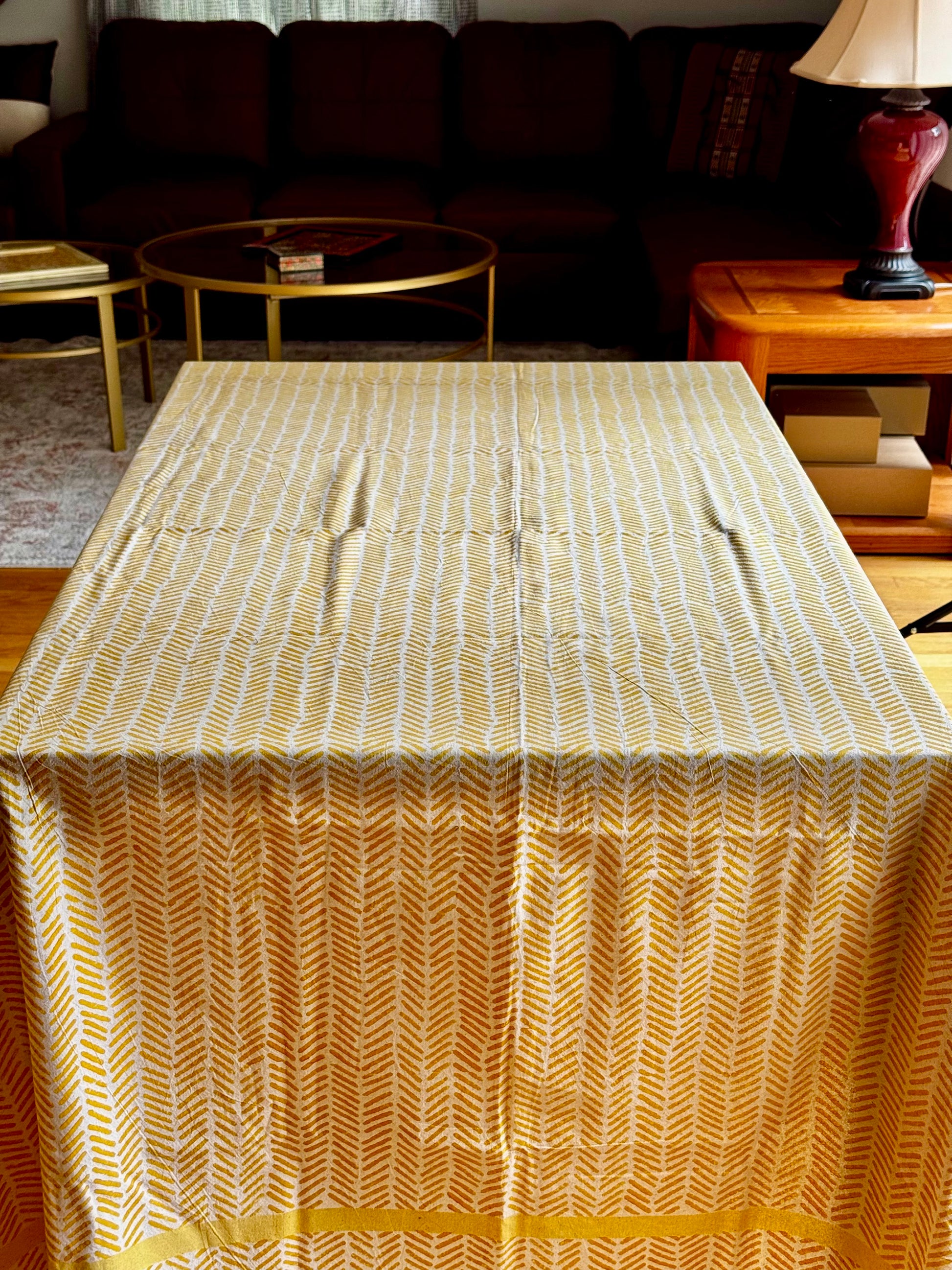 Table with a gold and white patterned hand block print tablecloth in a living room setting.