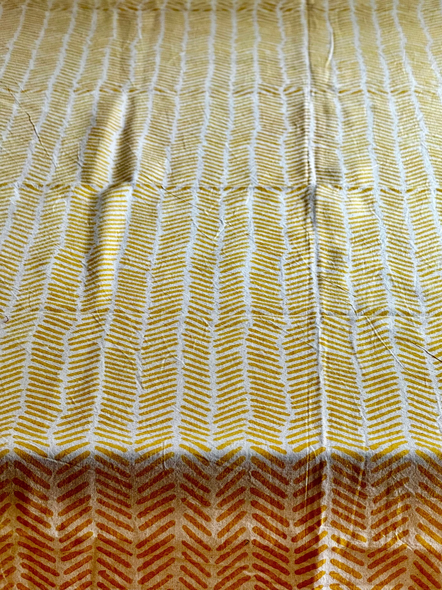Hand block printed tablecloth closeup  with a pattern of white lines on a yellow background