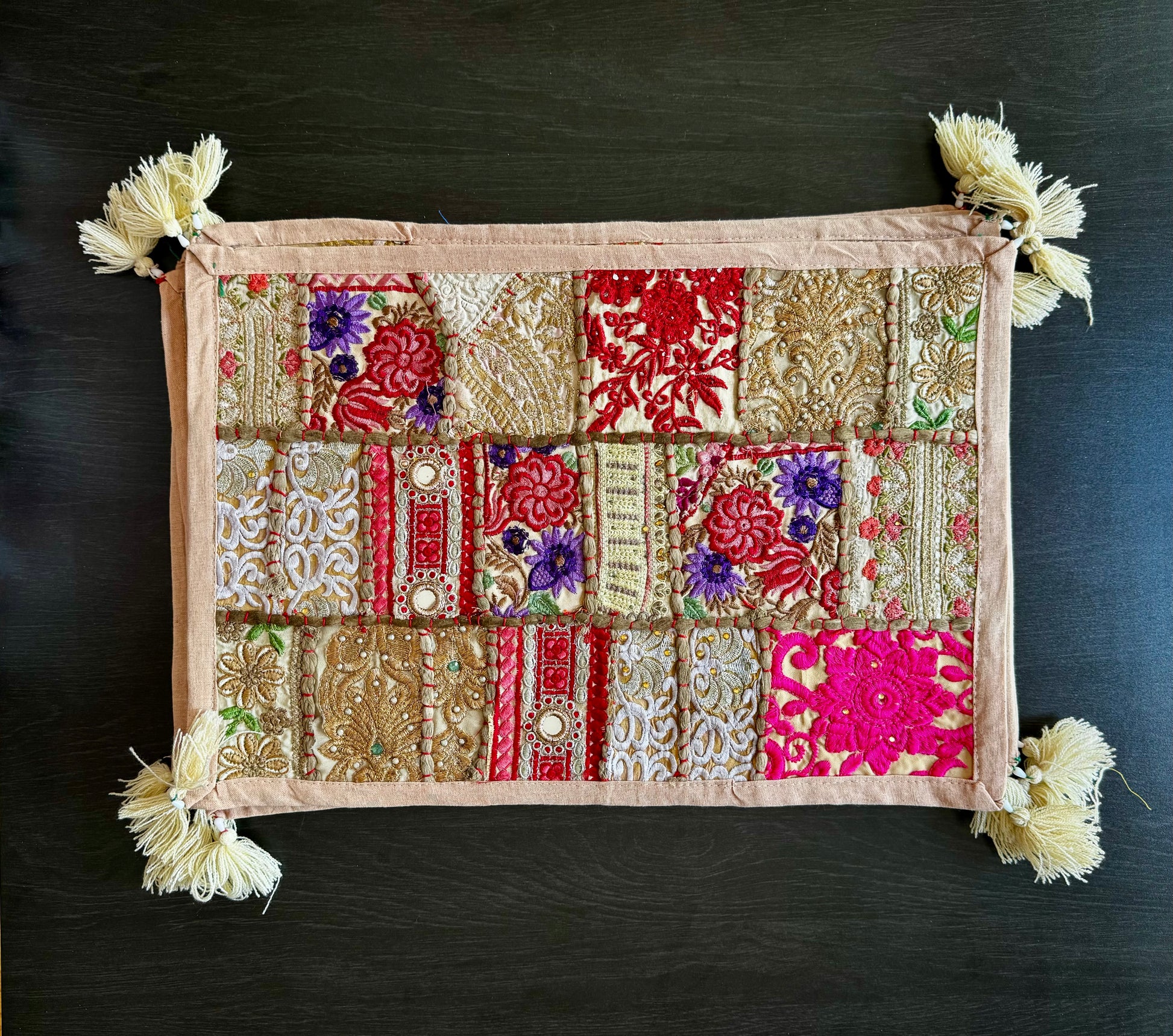 Decorative Khambhadia patchwork placemats with floral and geometric patterns on a dark background